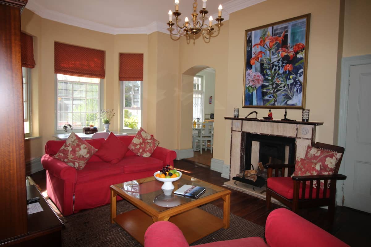 A living room with a red sofa, a wooden coffee table with a bowl of fruit, and a painting on the wall.
