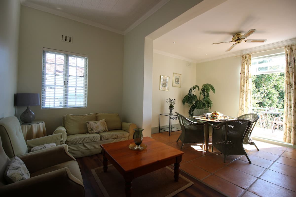 A living room with a sofa, coffee table, and dining area with chairs and a table.