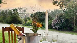 A table with a champagne bottle in a metal bucket, a candle, and two wine glasses. - Zuurberg Mountain Village (Addo)