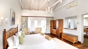 A spacious bedroom with a large bed, wooden furniture, and a chandelier. - Zuurberg Mountain Village (Addo)