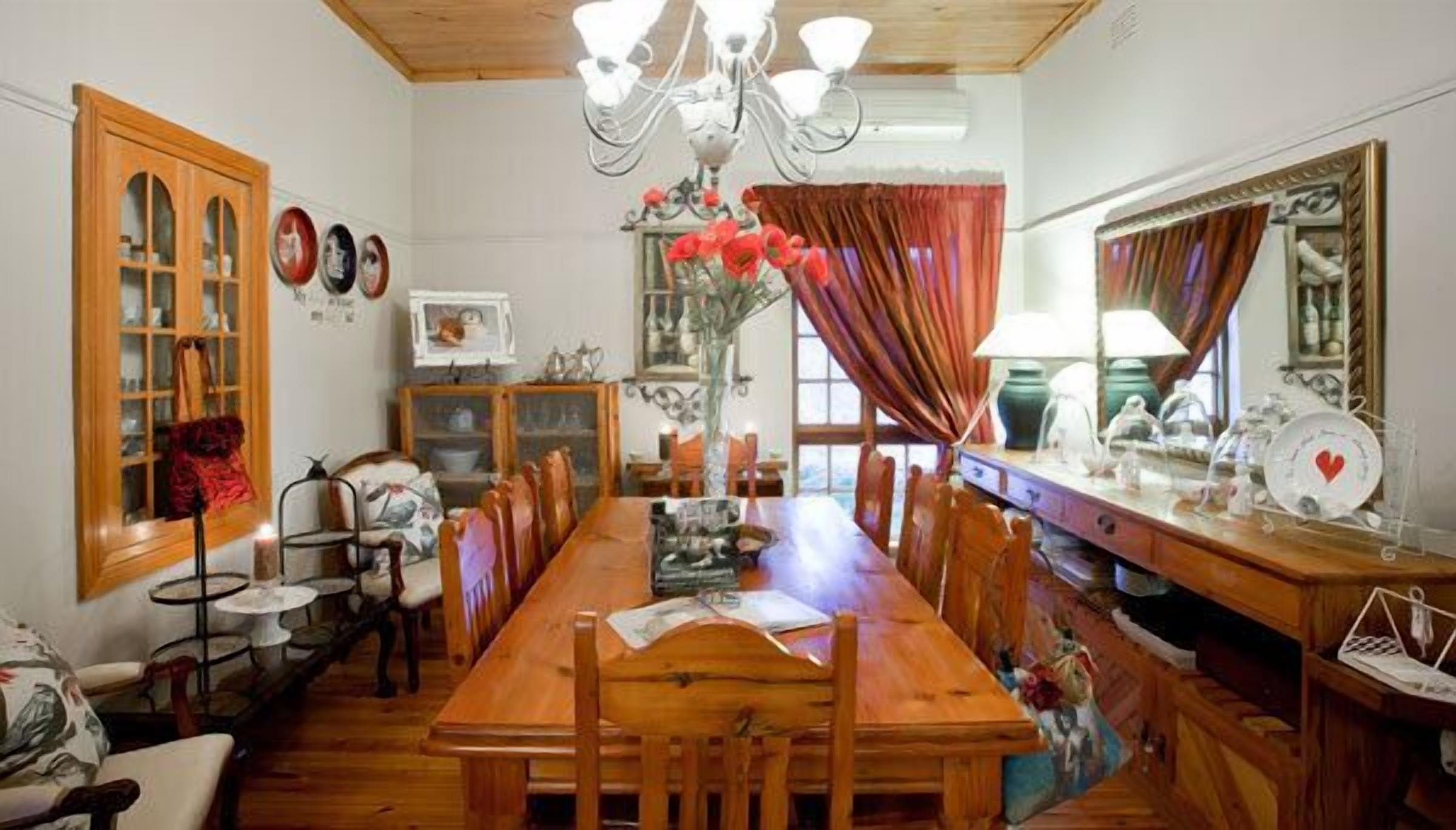 A dining area with a wooden table, chairs, a chandelier, and a cabinet with glass doors.