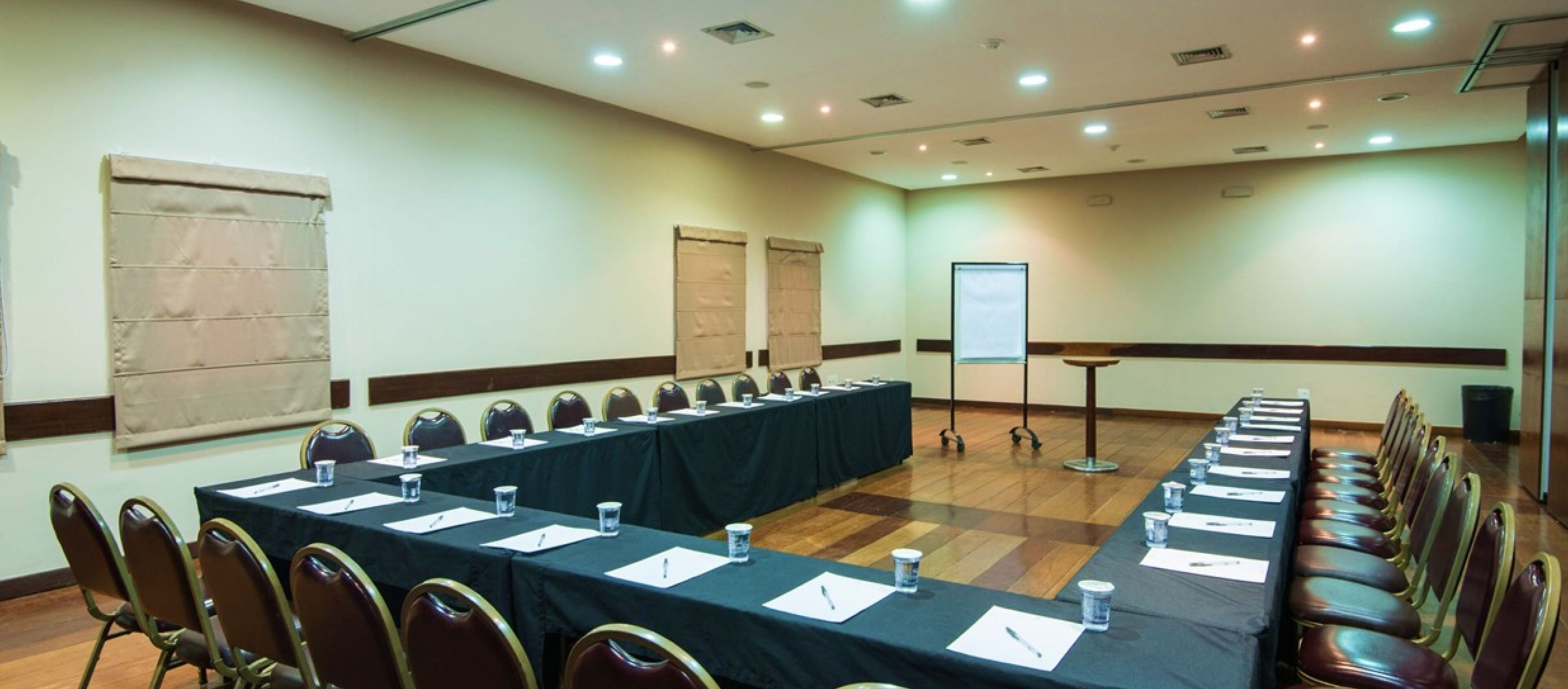 A conference room with a long table, chairs, and a projector screen.