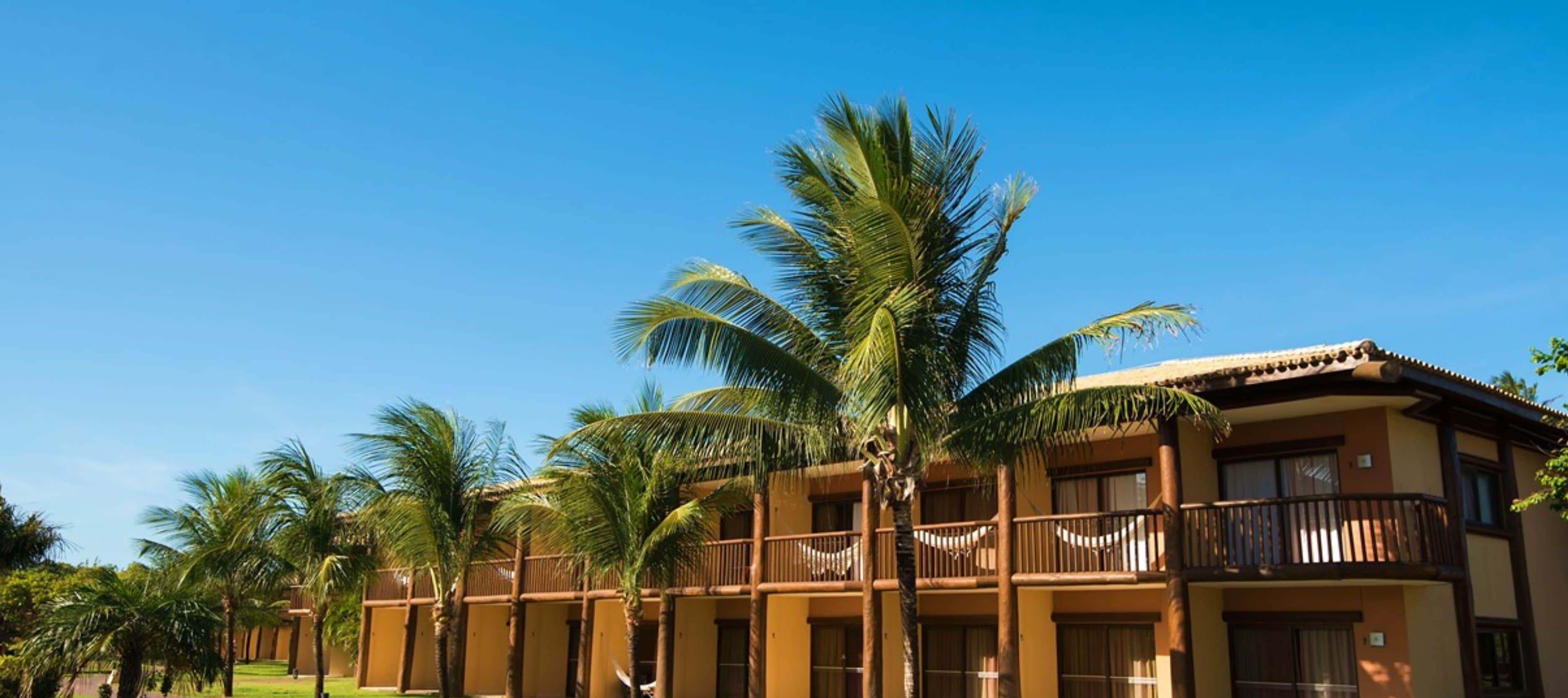 A multi-story hotel with balconies and palm trees.