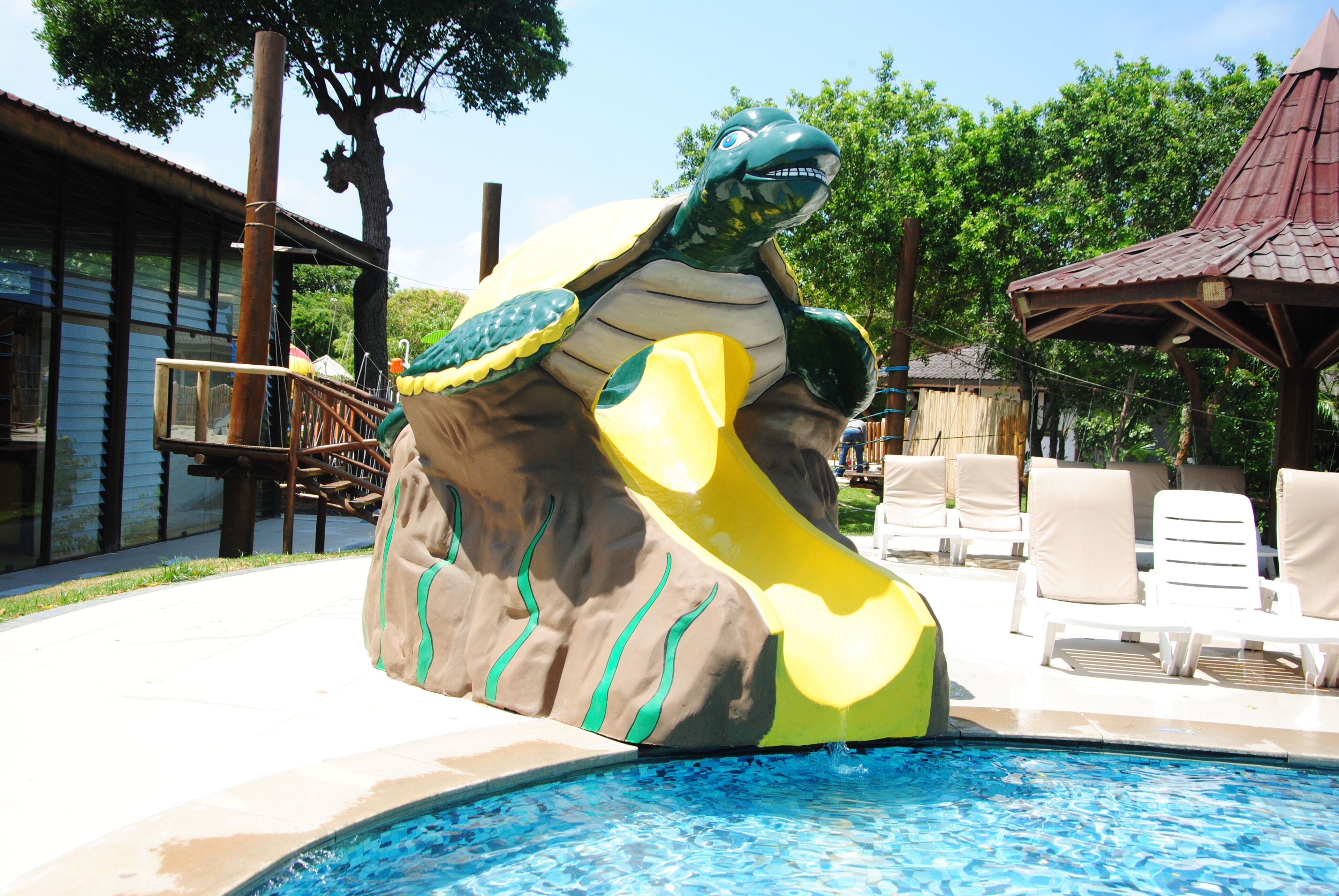 Une piscine agrémentée d’une grande sculpture de tortue, de chaises longues et d’une terrasse en bois.