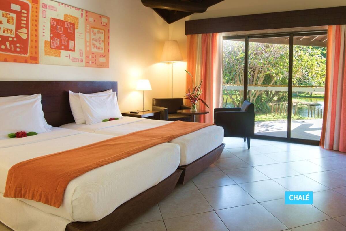 A hotel room with a large bed, a desk, a chair, and a view of the outdoors.