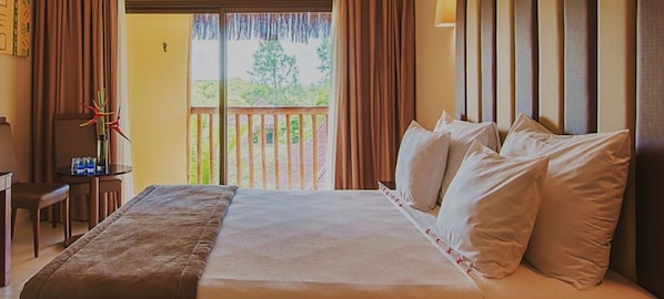 A hotel room with a large bed, a desk, and a view of the outdoors. - Vila Galé Resort Marés - All Inclusive (Camaçari)