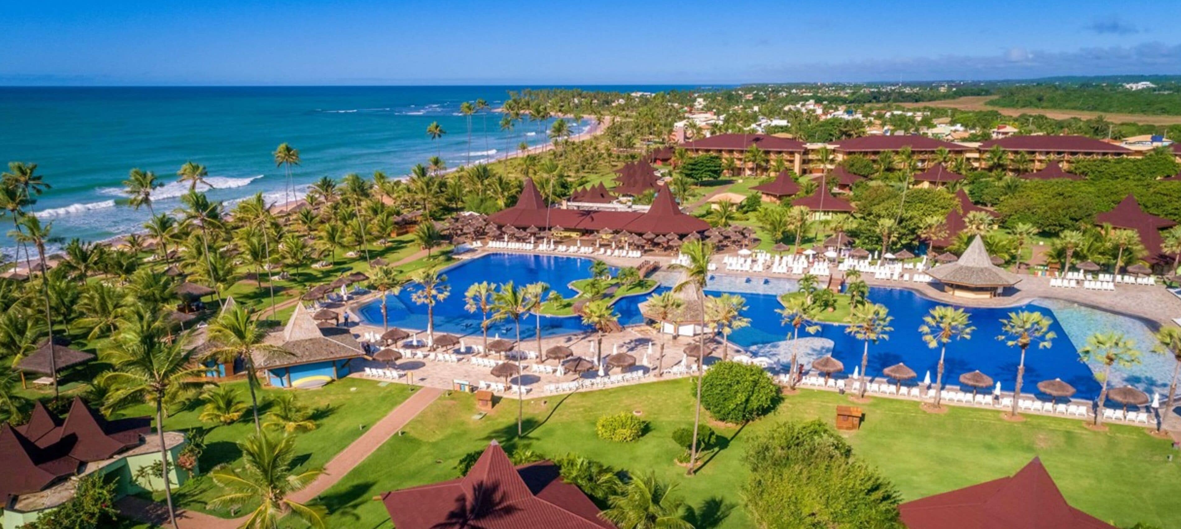 A resort with multiple swimming pools, palm trees, and beachfront views.