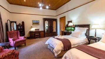 A hotel room with two beds, a wooden ceiling, a large mirror, a dresser, a chair, and a lamp.