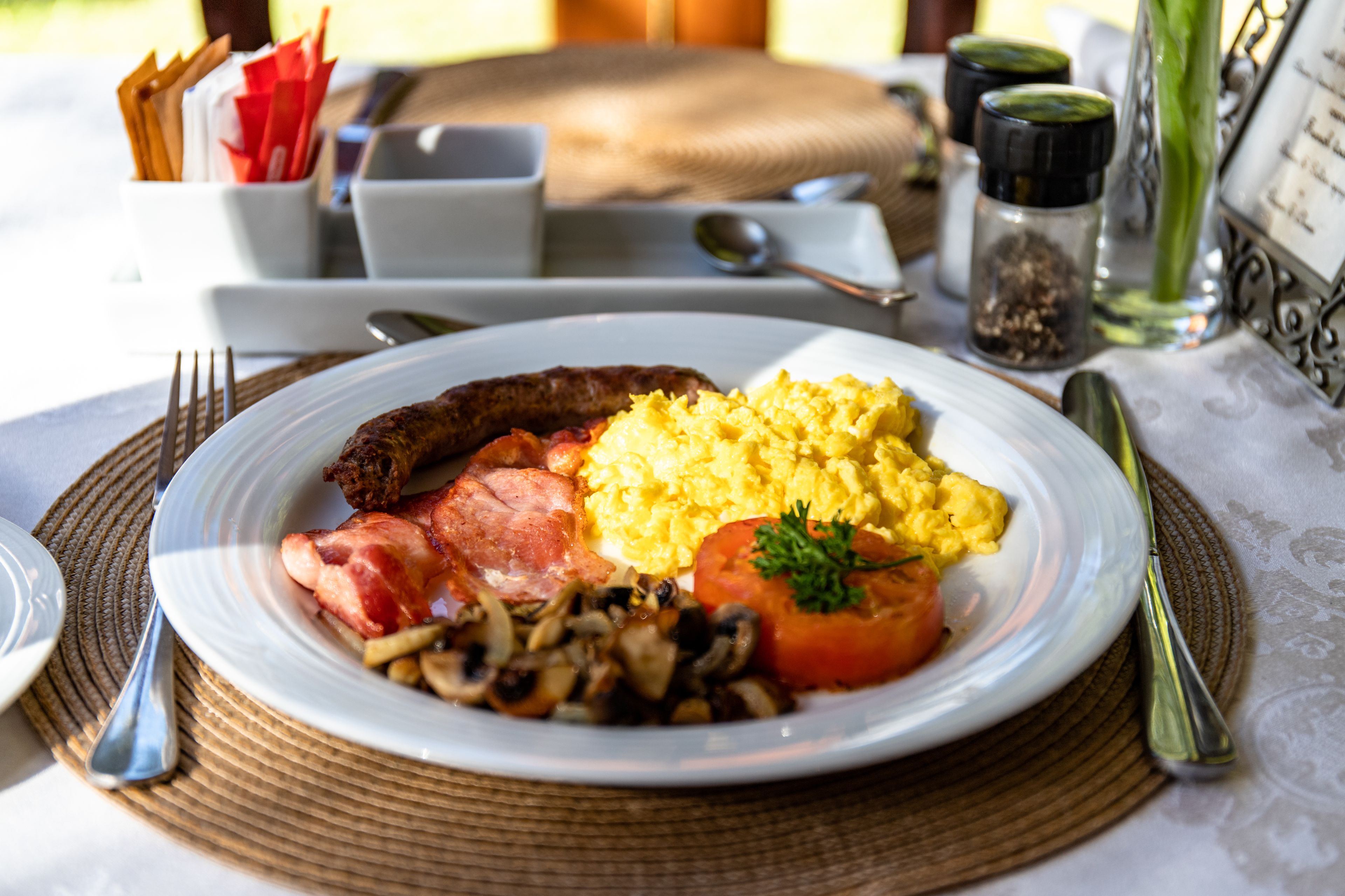 Ein Teller mit Frühstücksei, Speck, Tomaten und Pilzen.