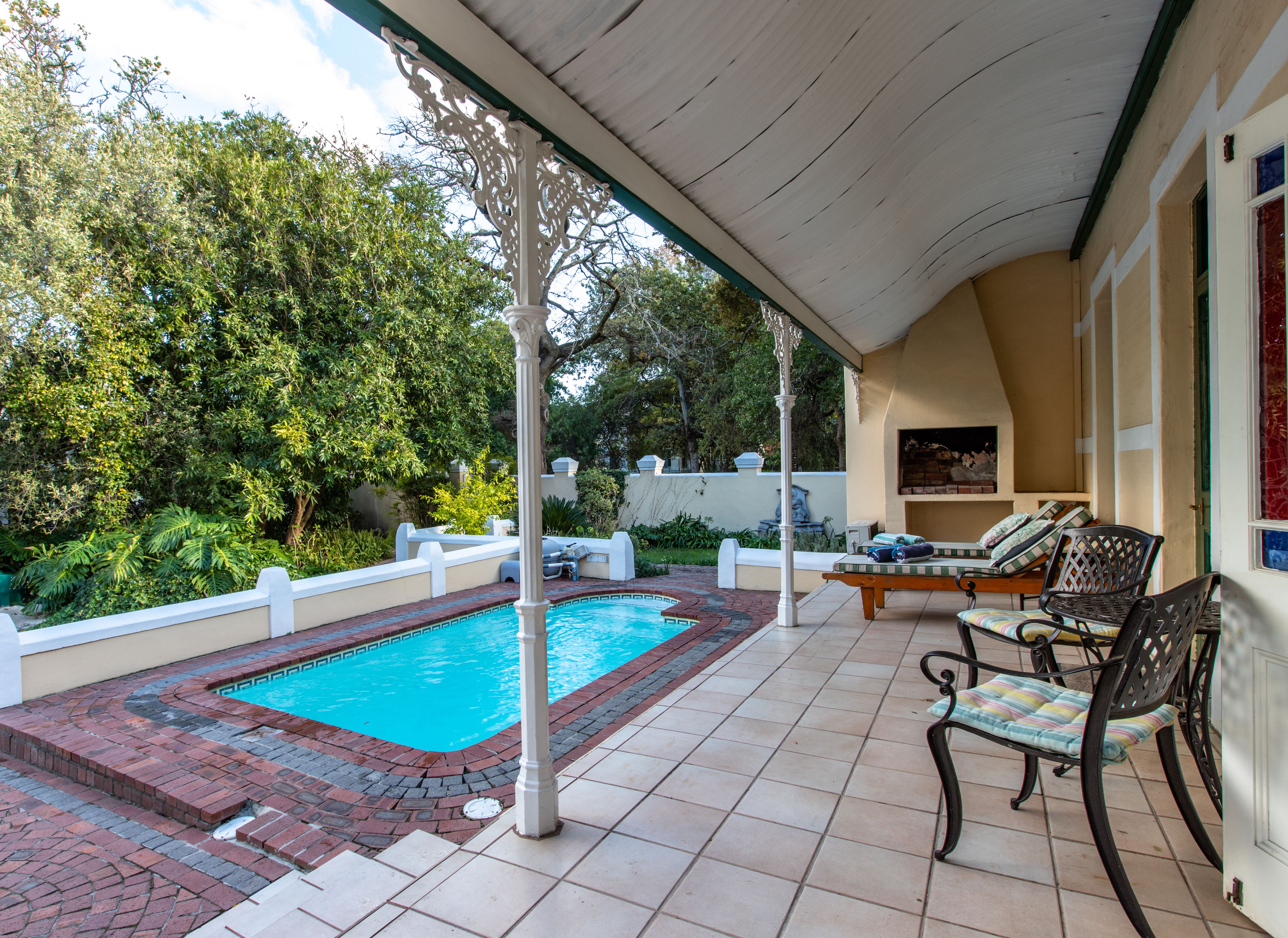 A covered outdoor area with a swimming pool, lounge chairs, and a pergola.