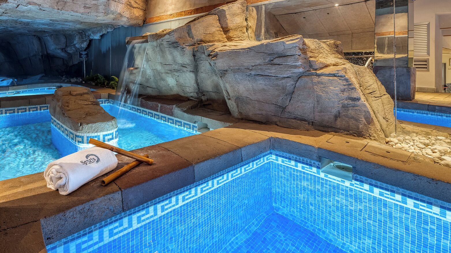 A spa area with a pool, a towel, and a rock formation.