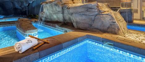 A spa area with a pool, a towel, and a rock formation.