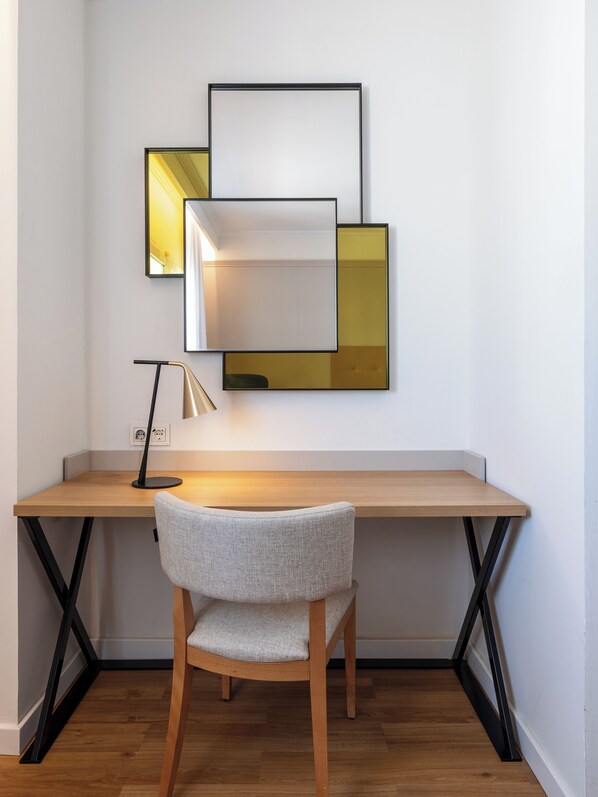 Un espacio de trabajo moderno con un escritorio de madera, una silla y un espejo fijado a la pared.