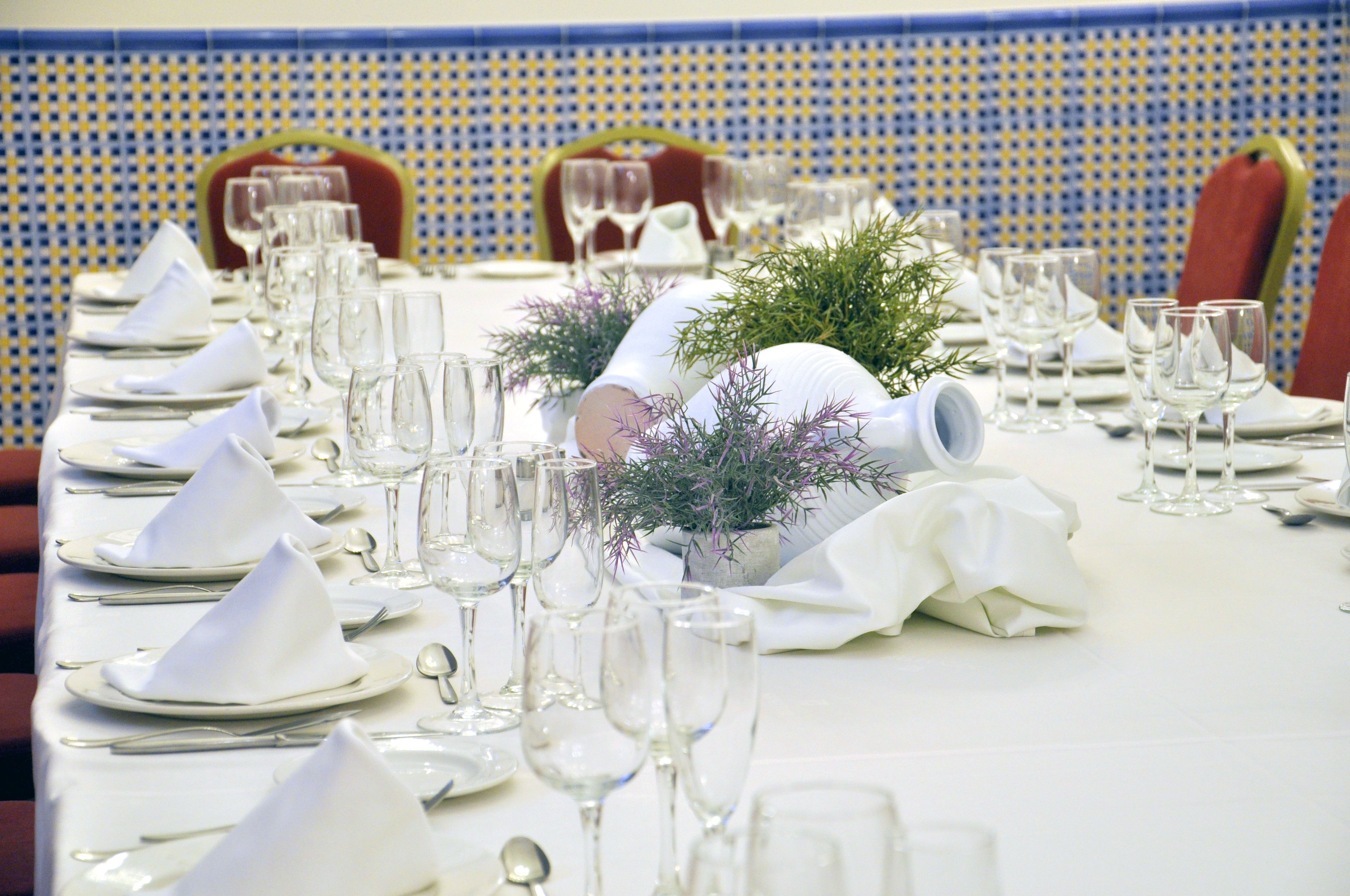Una mesa servida para una cena formal, con manteles blancos, cubiertos y copas de vino.