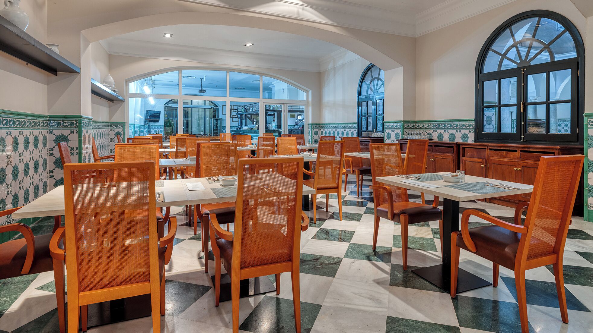 A spacious restaurant with high ceilings, large windows, and a checkered floor.
