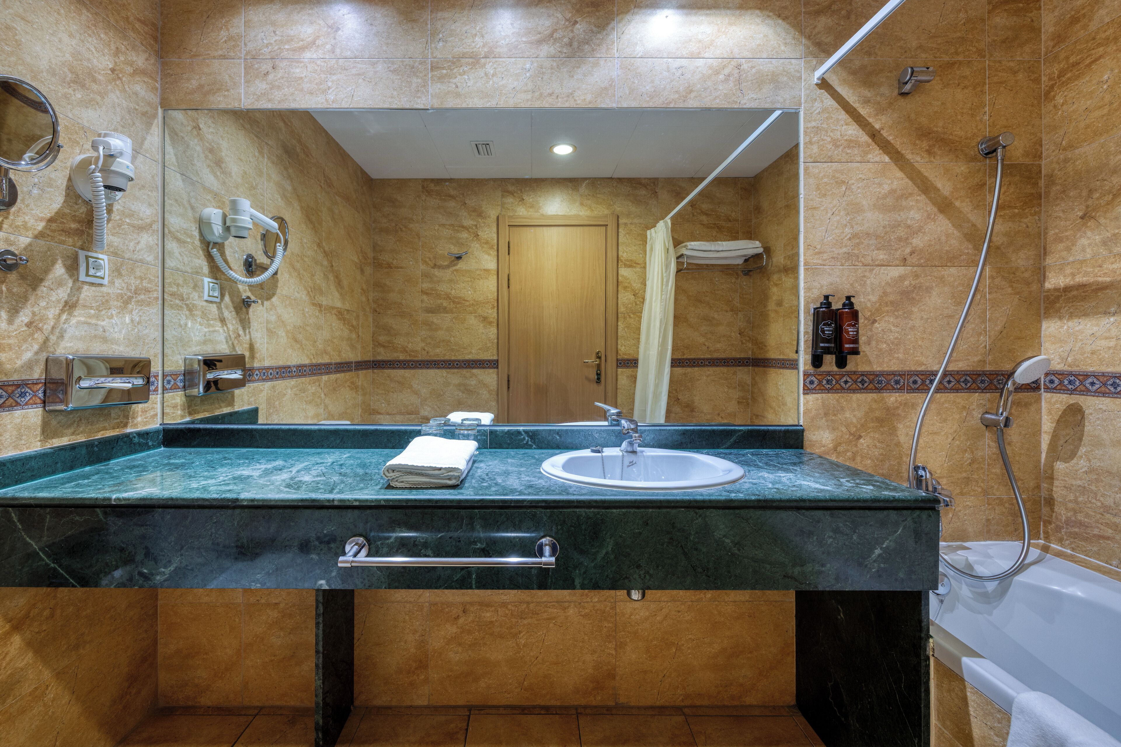 A bathroom with a marble sink, a mirror, a towel rack, and a shower area.