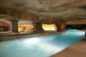 Una piscina interna con pareti in pietra e superficie d'acqua cristallina.