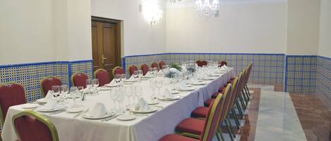 A long banquet table set for a formal event, with red chairs and white tablecloths.