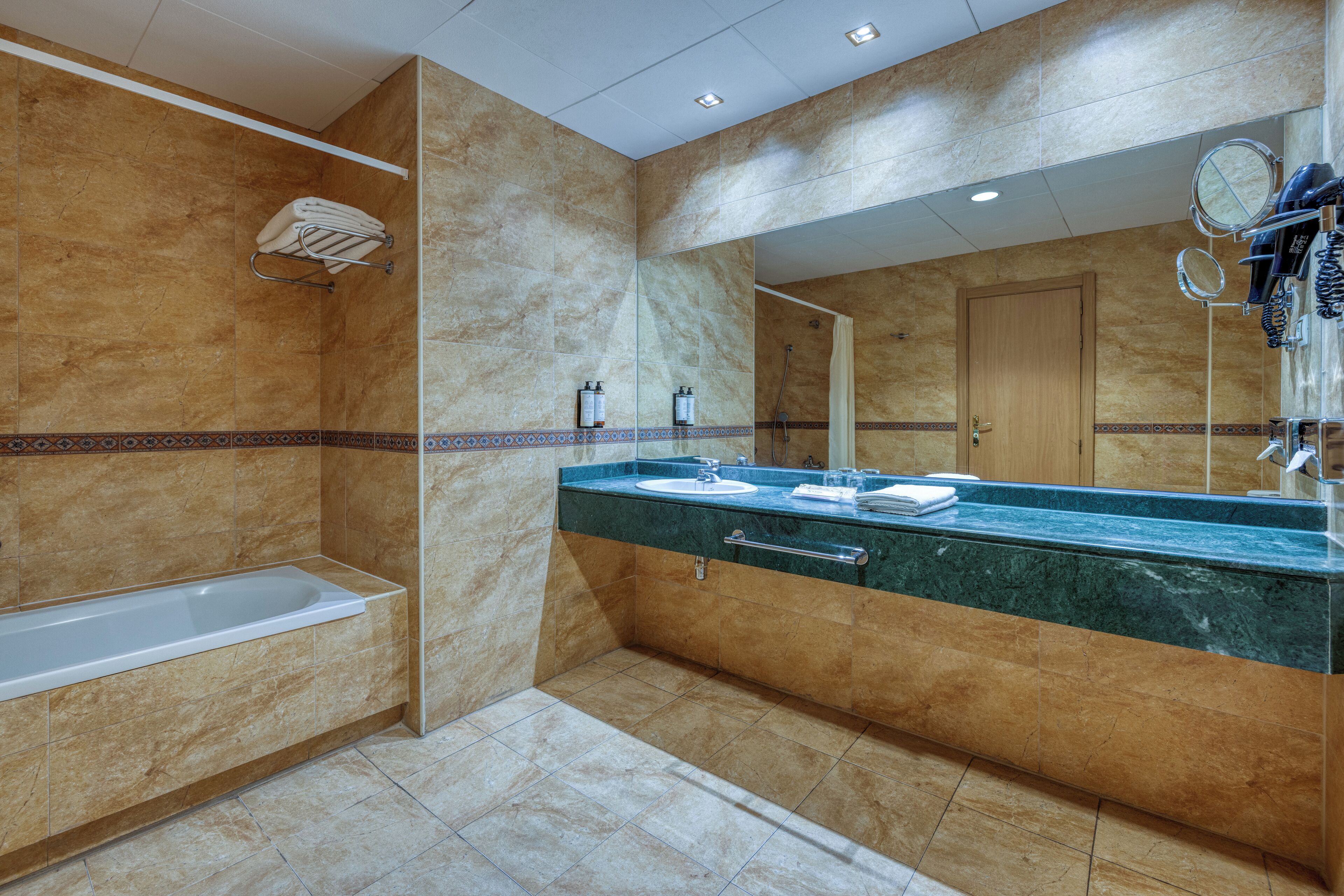 A modern bathroom with a bathtub, a sink, and a large mirror.