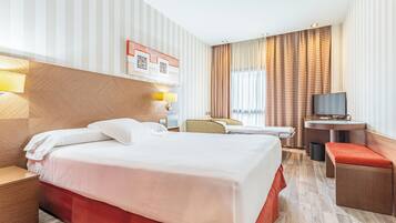 Una camera d'albergo con un letto, comodino, lampada, televisore e una piccola scrivania con sedia.