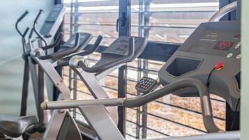 A row of stationary bikes in a gym with a window view.