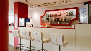 A bar area with a red accent wall, a variety of liquor bottles, and modern bar stools.
