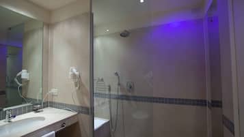 Un baño moderno con ducha envuelta en vidrio, tocador con lavabo y espejo.
