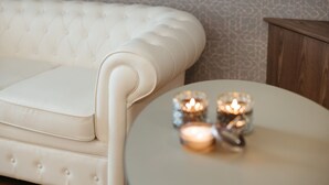 A white tufted sofa and a small round table with candles.