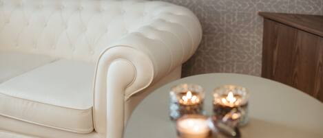 A white tufted sofa and a small round table with candles.