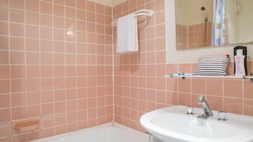 A bathroom with pink tiled walls, a white sink, and a bathtub.