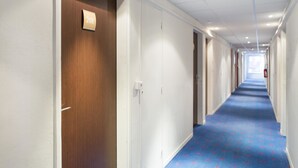 A long, narrow hotel corridor with a blue carpet and white walls. - Les Gens de Mer Dunkerque (Dunkirk)