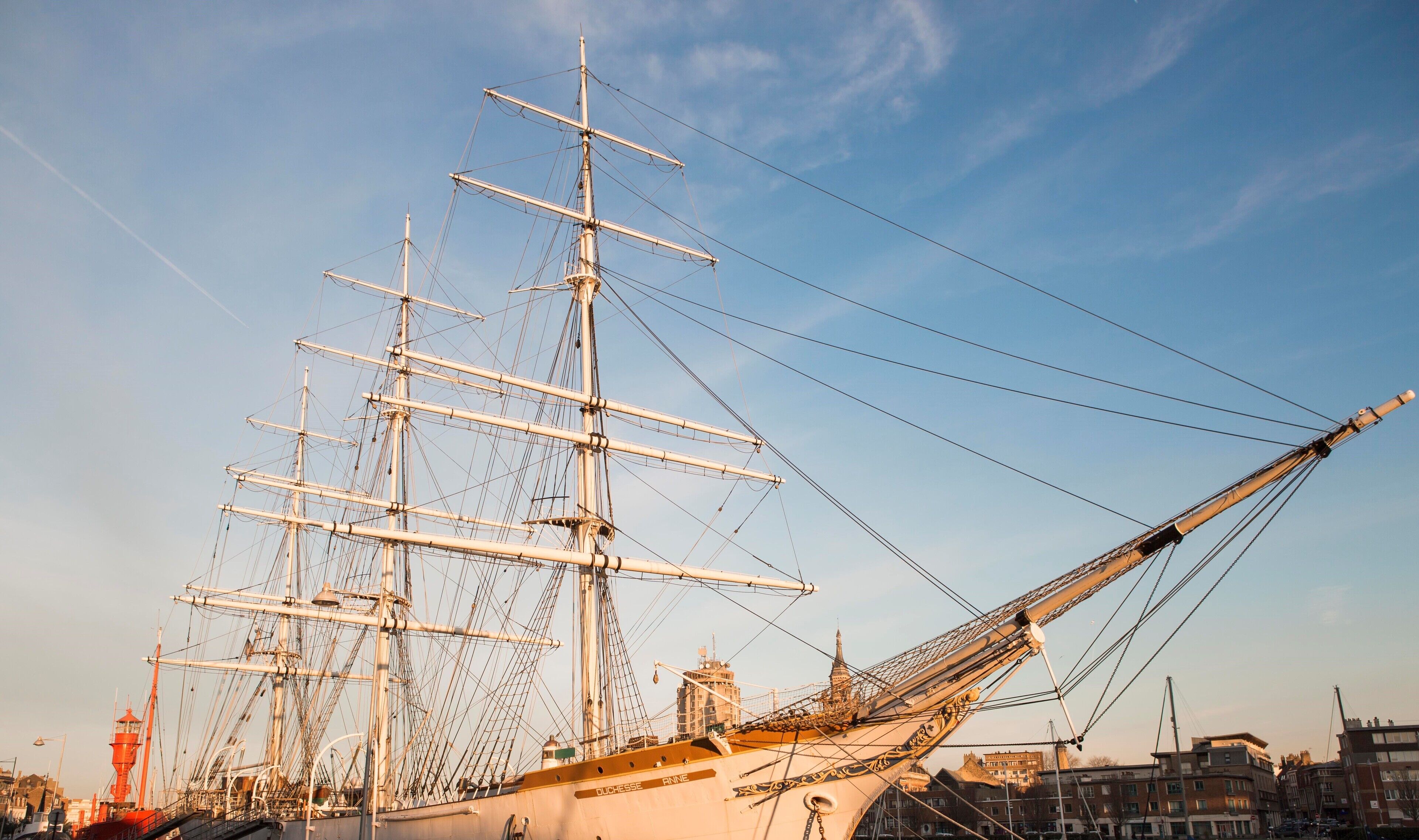 A large sailing ship docked at a harbor with multiple masts and rigging.