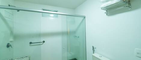 Une salle de bain avec une douche à parois de verre, des toilettes, un lavabo avec un plan de travail en granit et un porte-serviettes fixé au mur.