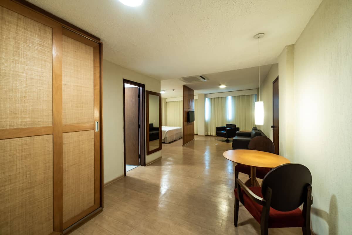 Una habitación de hotel con piso de madera, una cama, un escritorio y una silla.