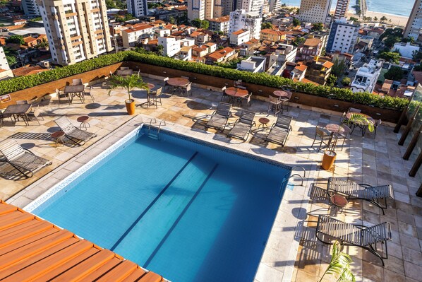 A rooftop pool with lounge chairs and tables, surrounded by a cityscape. - Hotel Praia Centro (Fortaleza)