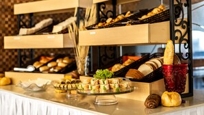 A buffet with various food items including bread, pastries, and a glass cake stand. - Hotel Praia Centro (Fortaleza)