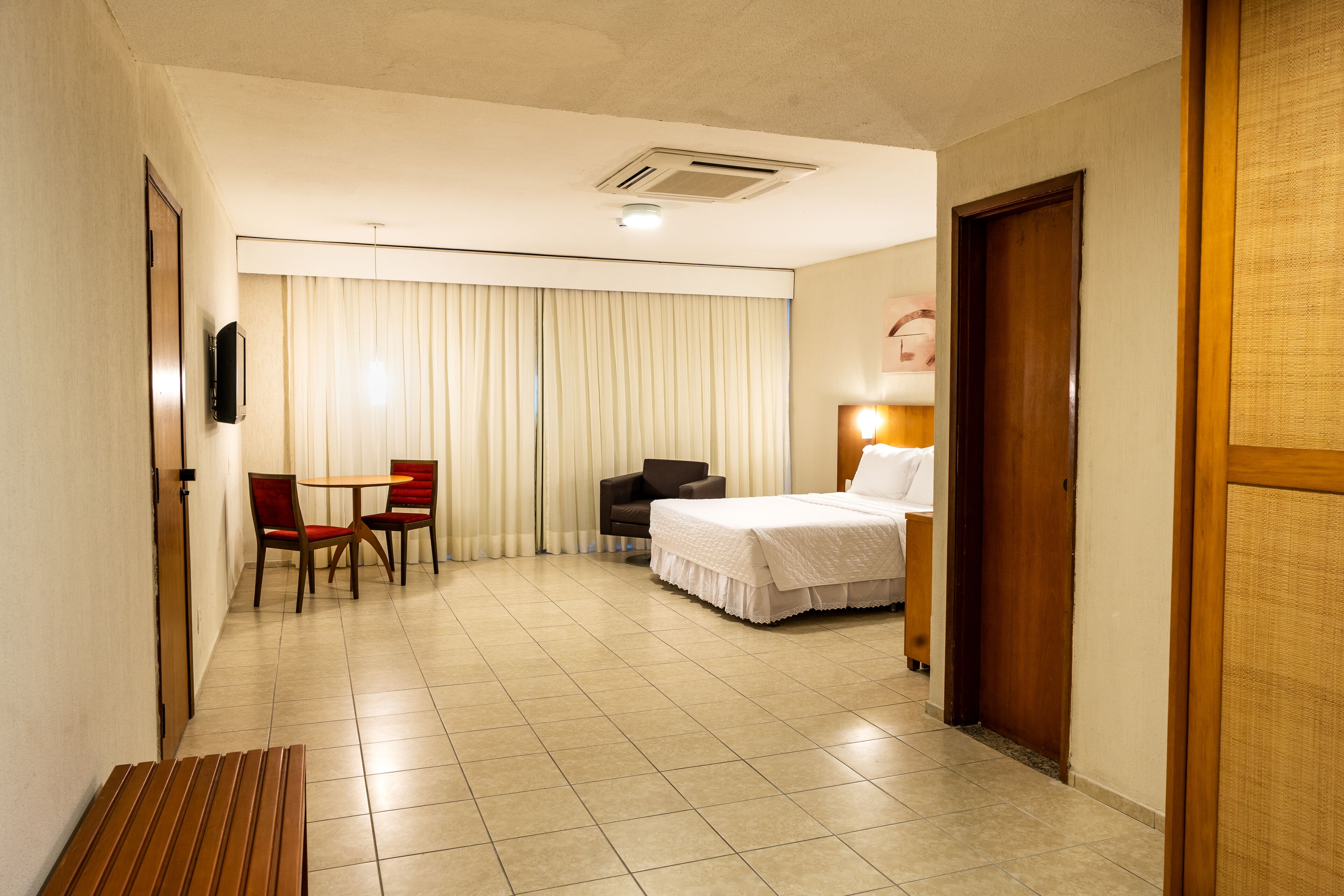 A hotel room with a bed, a desk, a chair, and a television.