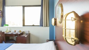 Een hotelkamer met een bed, een bureau en een raam met gordijnen.