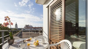 A balcony with a table set for breakfast, including croissants, orange juice, and coffee.