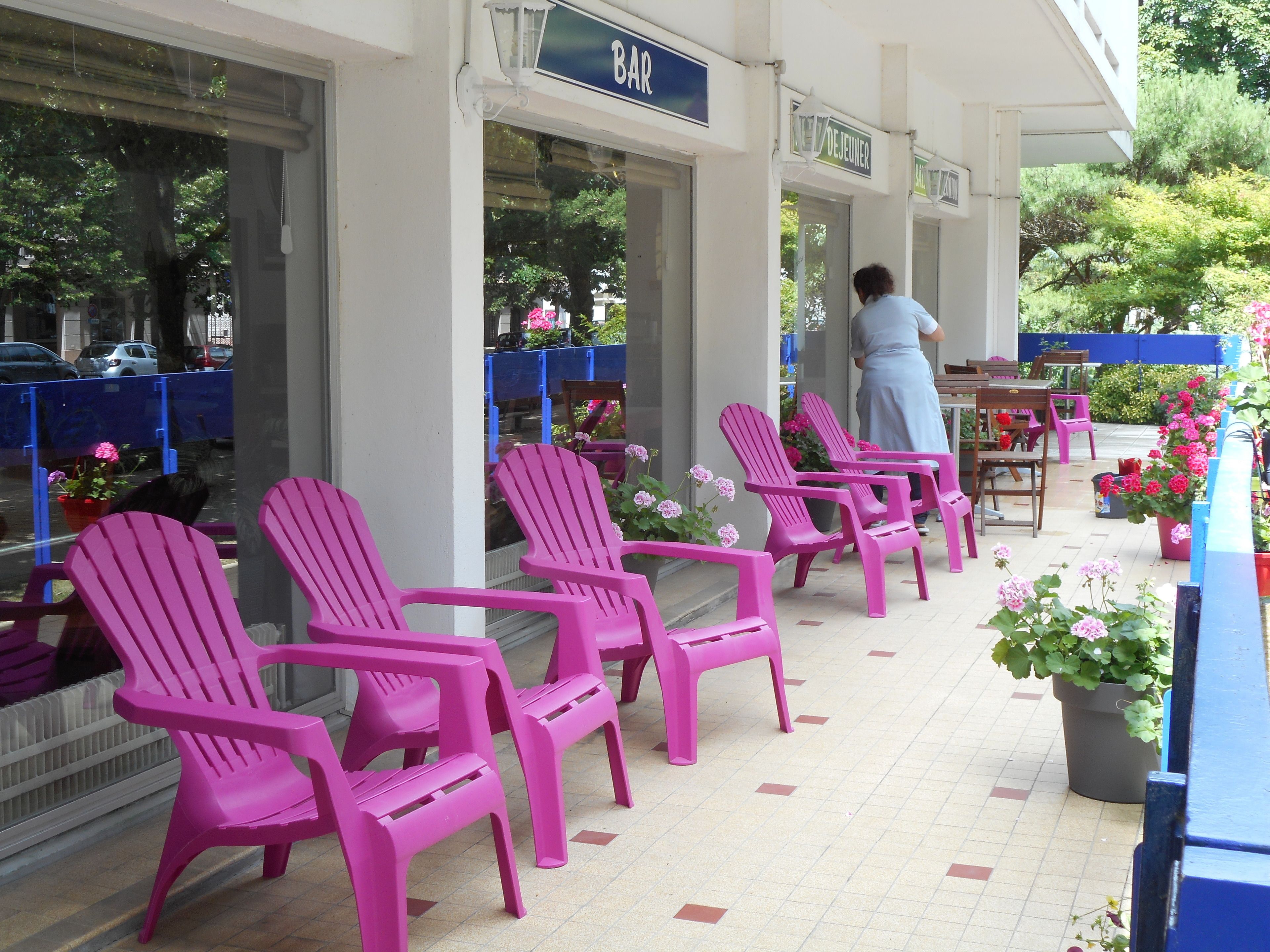 Un bar avec des chaises roses et des plantes en pot à l’extérieur.