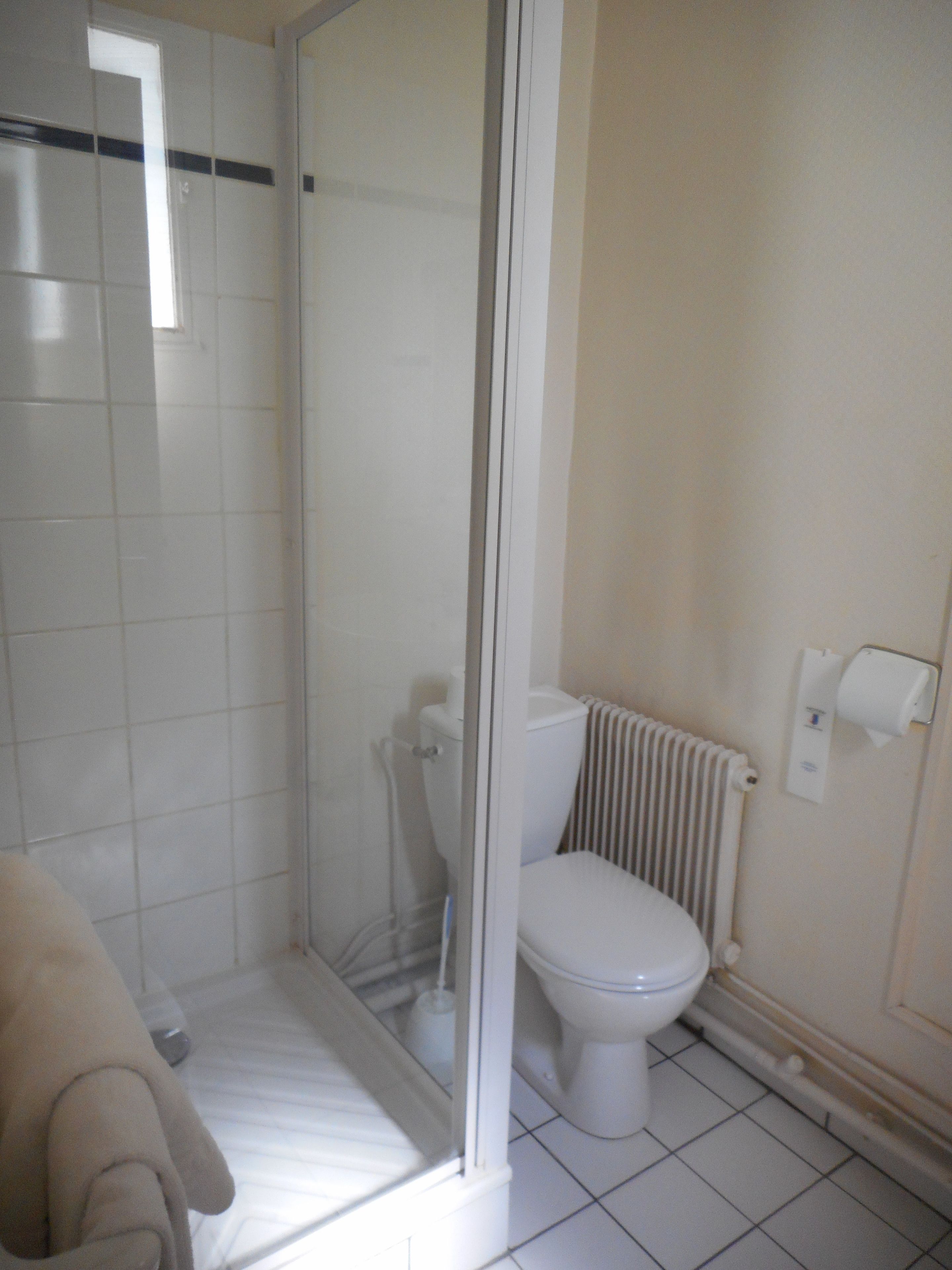 A bathroom with a toilet, a shower enclosure, and a radiator.