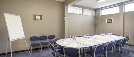A conference room with a large table, chairs, a whiteboard, and framed pictures on the walls.