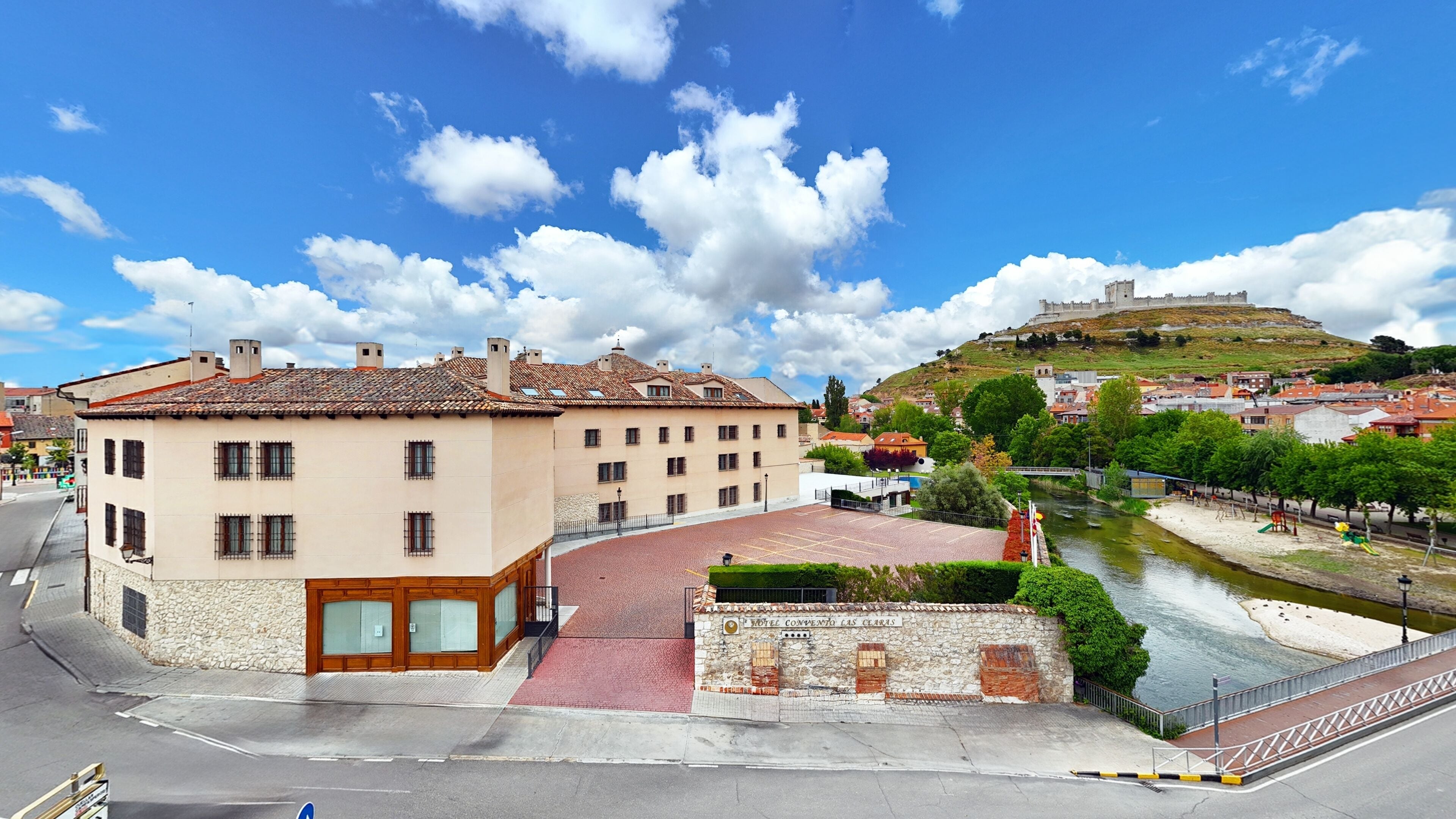 Un hotel con fachada de piedra, un patio interior y vistas al río.