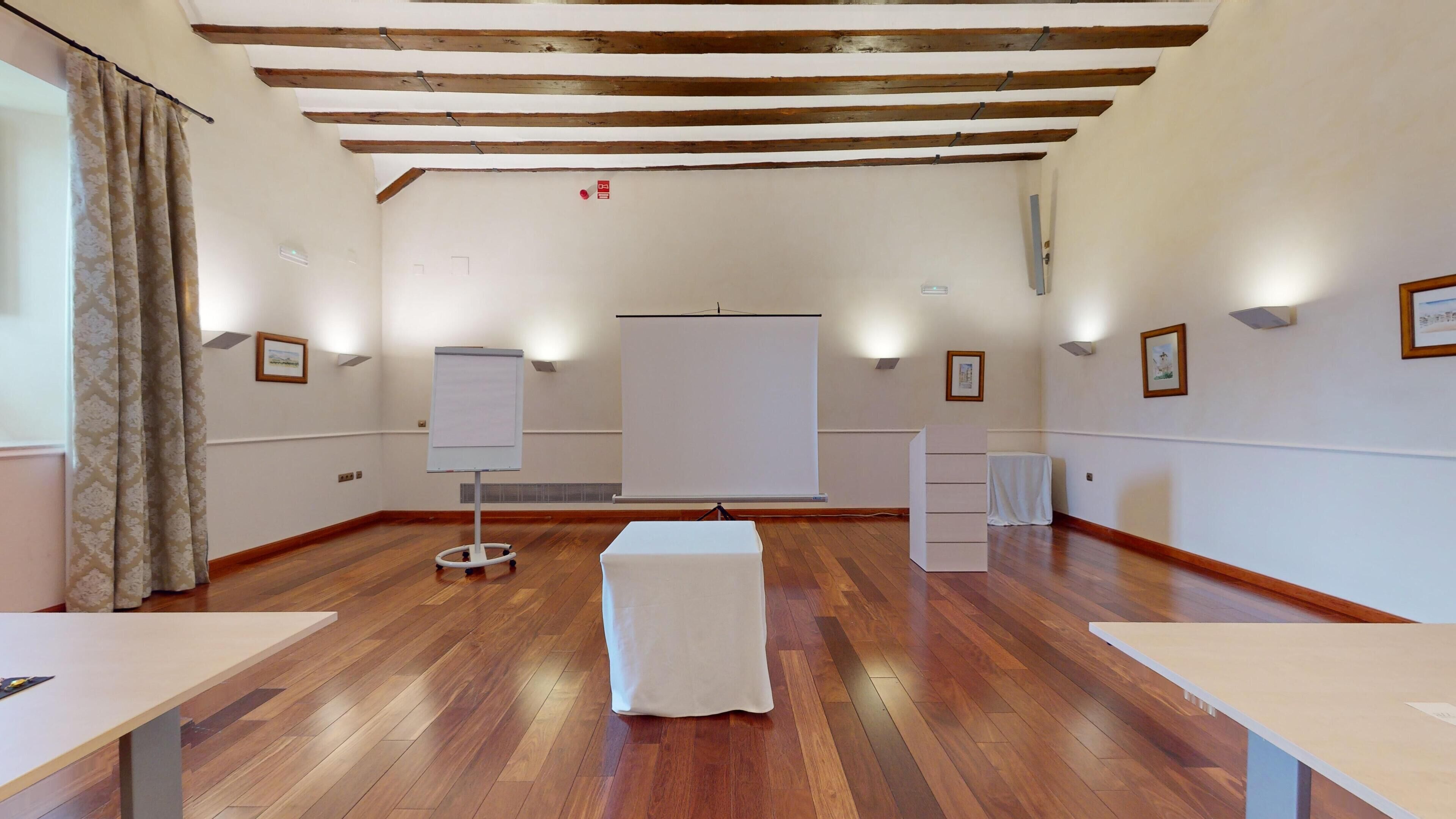 A conference room with wooden floors, white walls, and a whiteboard.