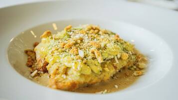 Un plato de comida con salsa cremosa y cobertura de nueces y pan rallado.