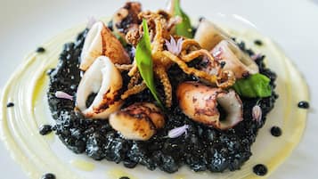 Une assiette de nourriture comprenant des calamars, des légumes verts et un risotto noir.