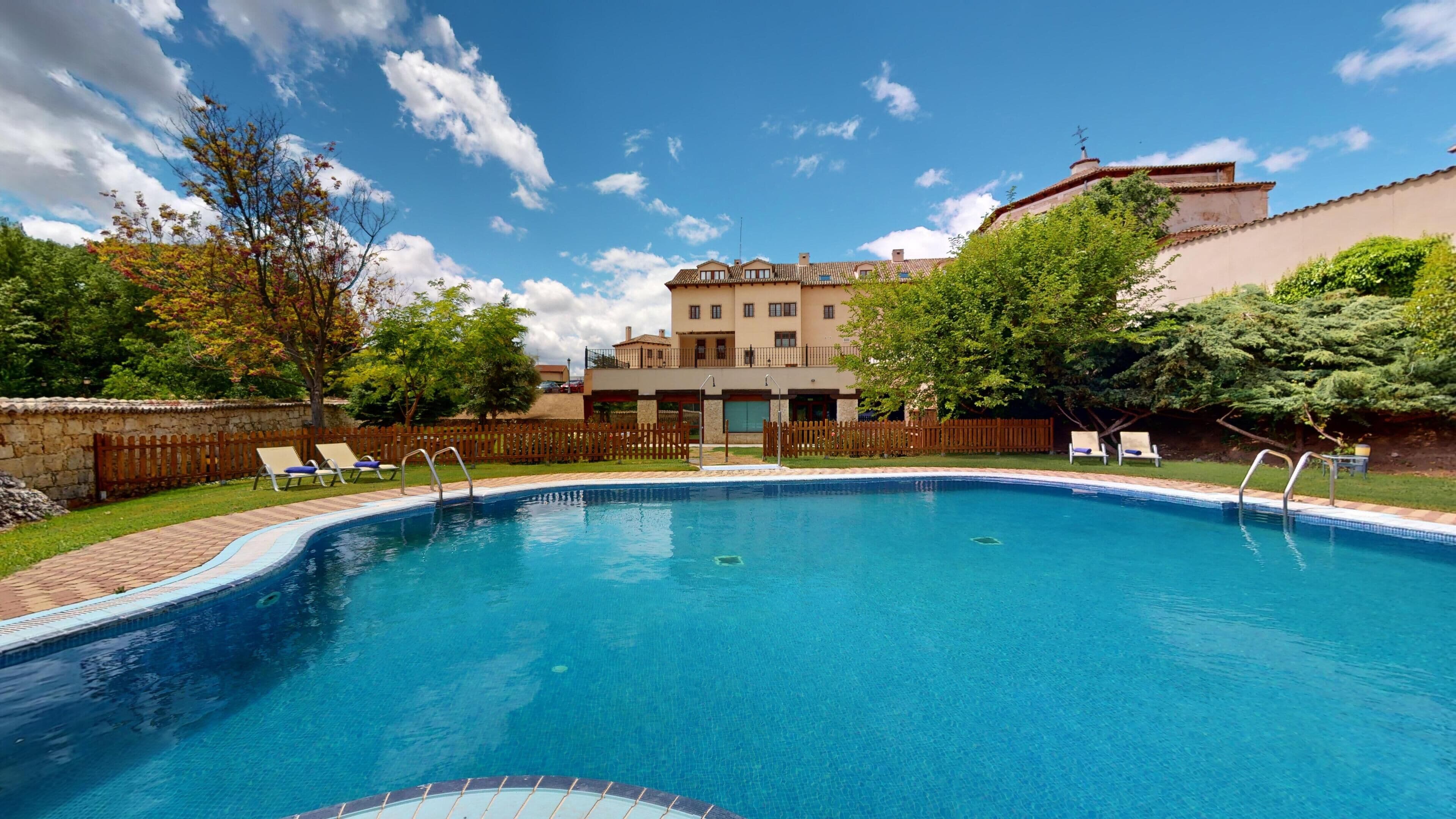 Una piscina con lettini e una parete in pietra.