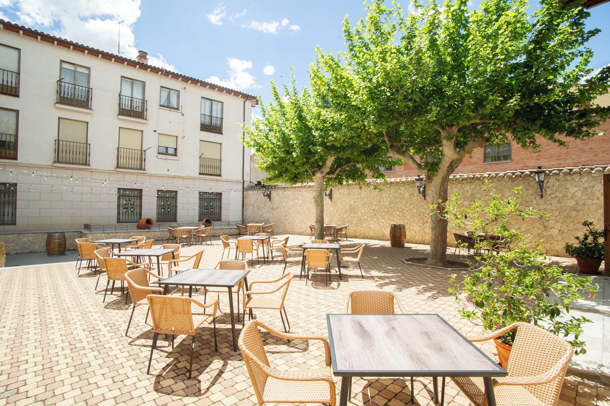 An outdoor patio with wicker furniture and a stone wall.
