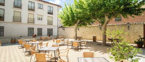 An outdoor patio with wicker furniture and a stone wall.