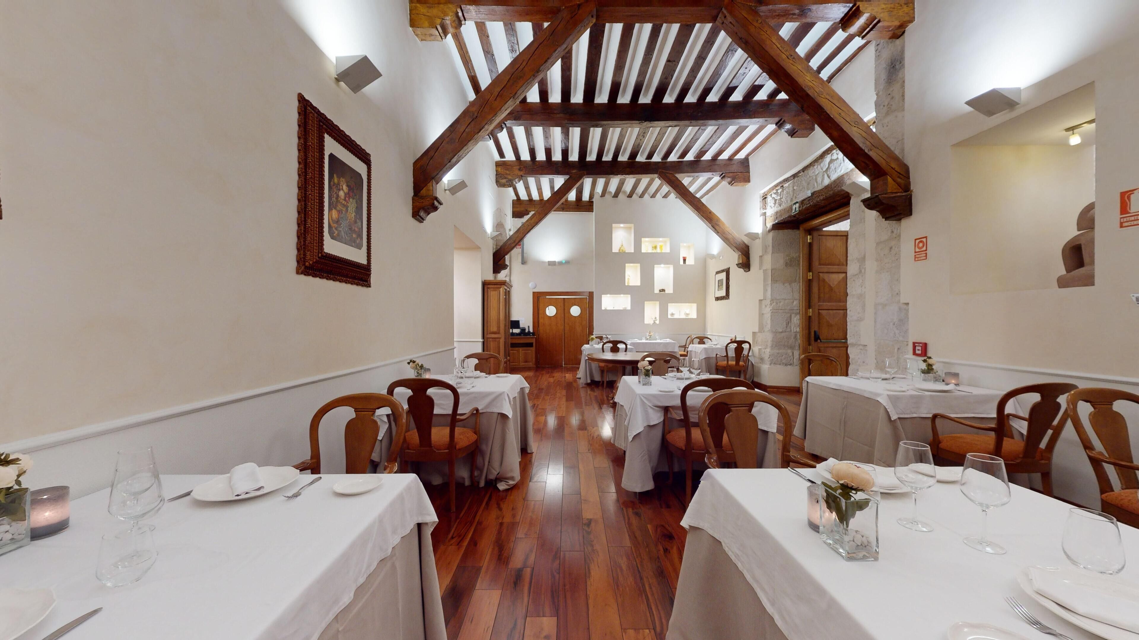 A restaurant with wooden beams, white tables, and chairs.